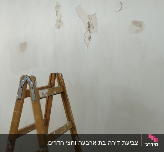 סולם עץ ליד קיר עם קילופי צבע